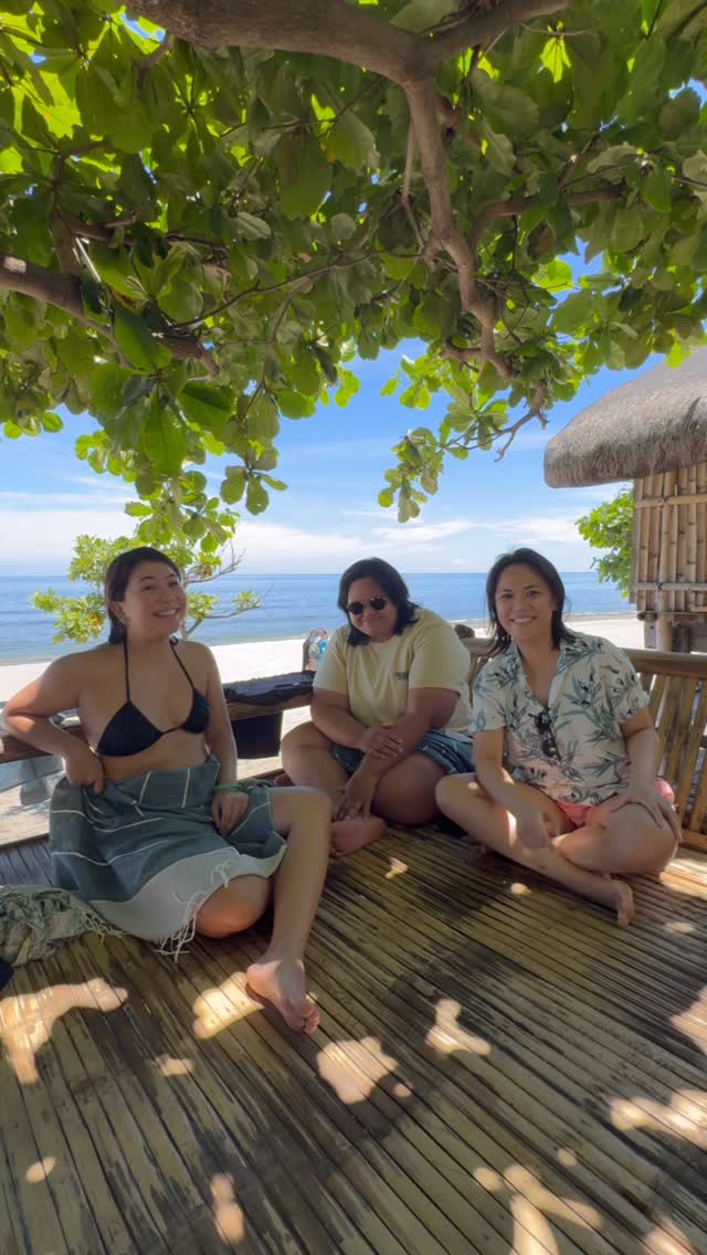 Guests lounging on Grover's outdoor Papag bamboo deck with La Union beach and ocean in the background